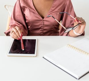woman sitting down with a ipad and notebook
