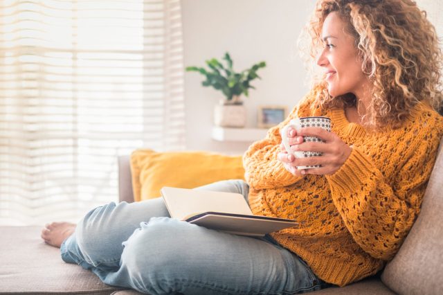 woman practicing self-care holding mug and reading