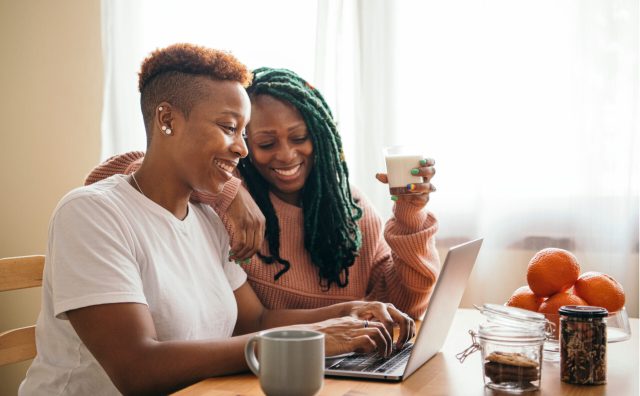 Happy lesbian couple finding storefront on laptop