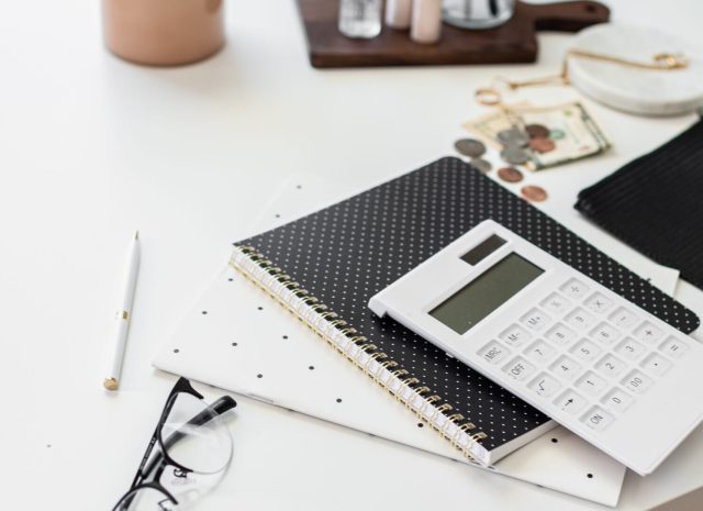 calculator, money and notebook set up to calculate how to economy proof your business