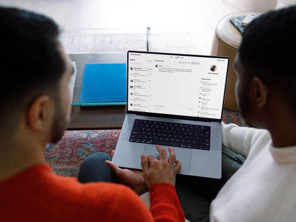 A couple looks at a laptop to send a inquiry to a wedding vendor