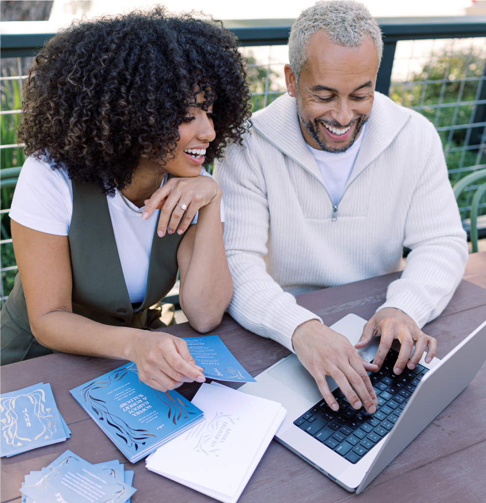 A man and woman look smile and look at a laptop