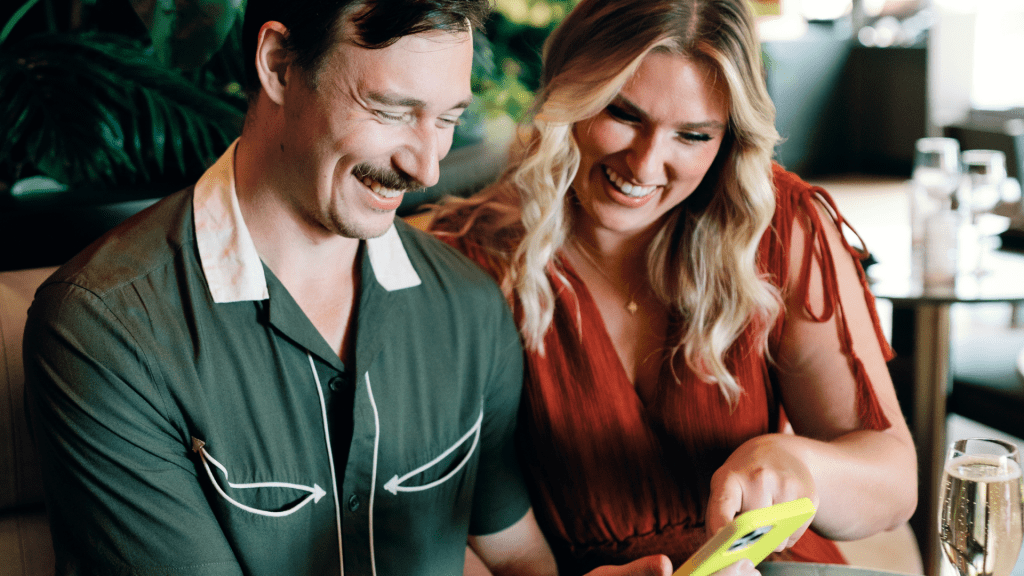 Engaged couple looks at a phone to browse wedding vendor listings.