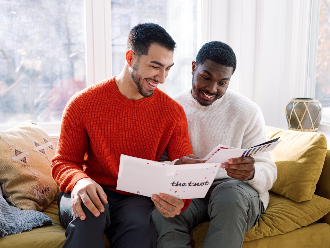 Happy male couple holding a The Knot booklet?