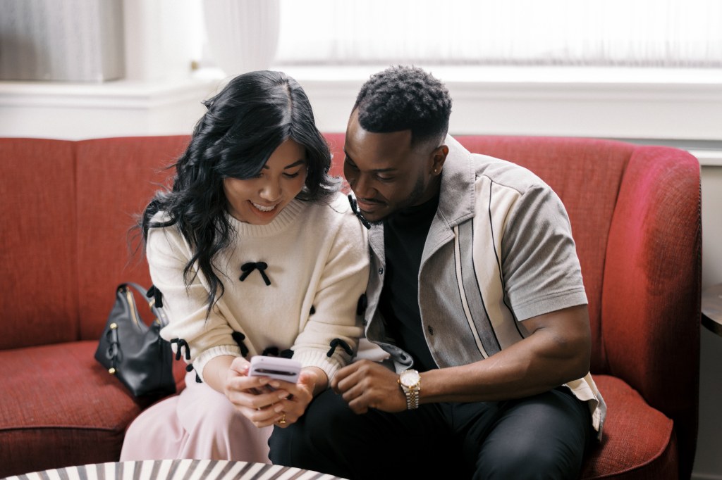 Couple sitting on couch with woman holding cell phone